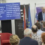 Na sliki je mag. Roman Rener, ki je udeležence nagovoril v imenu direktorja Geodetskega inštituta Slovenije Blaža Barboriča. Stoji za govorniškim pultom.